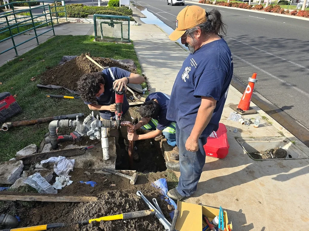 Plumbers working on a main line beside a street