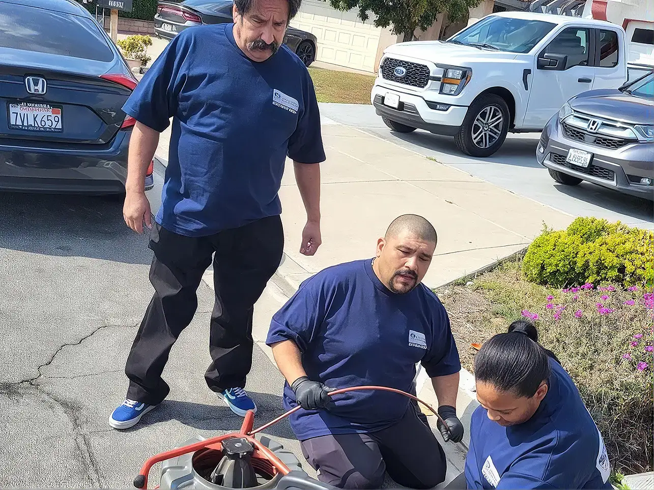 American Made Plumbing crew clearing a main line with a drain machine in a parking lot