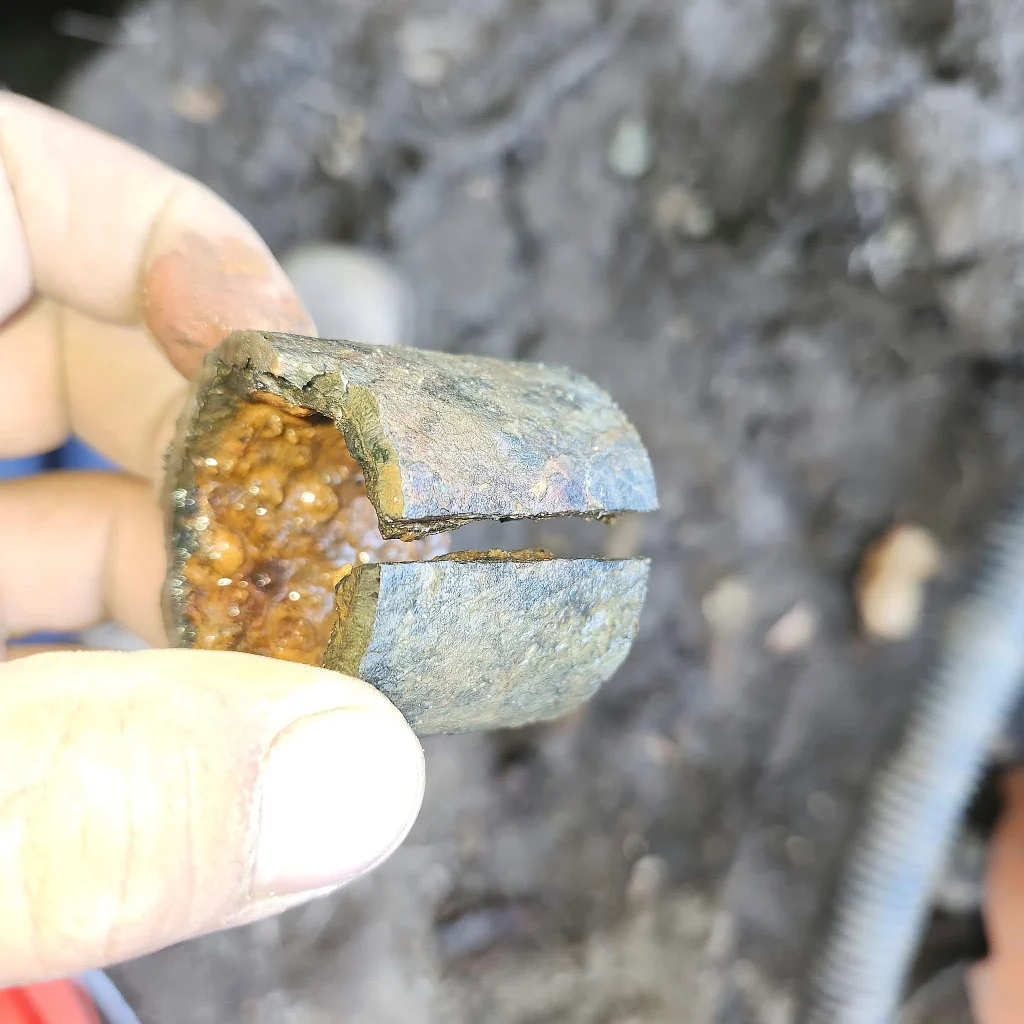 Hand holding a cut section of pipe packed with mineral scale