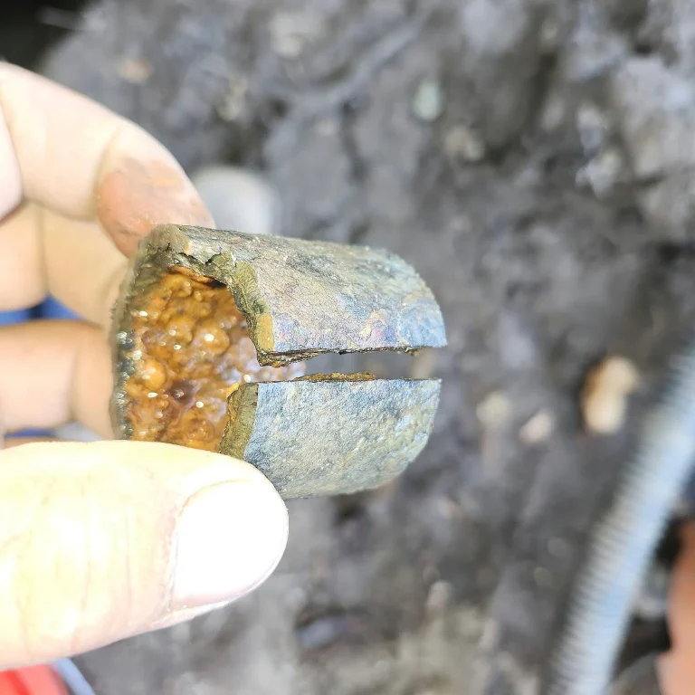 Hand holding a cut section of pipe packed with mineral scale
