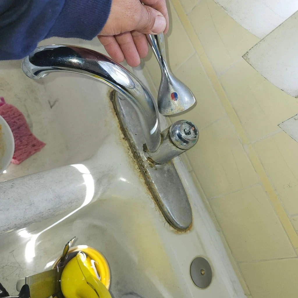 Hand turning on an older bathroom sink faucet