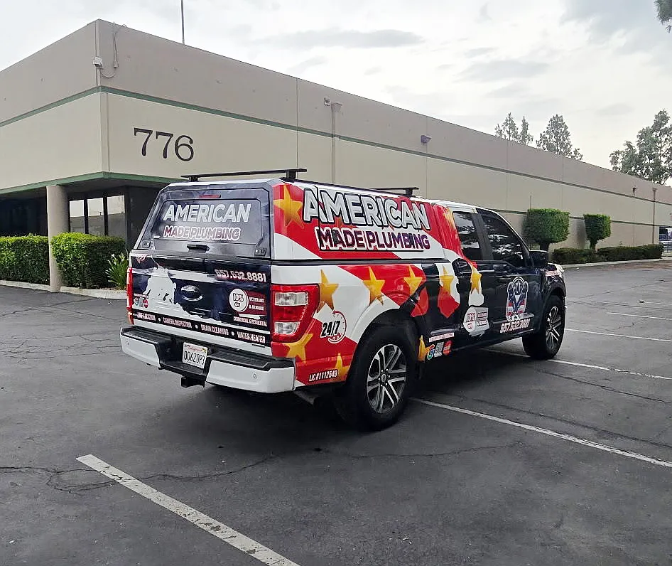 Rear of an American Made Plumbing service truck outside a commercial building
