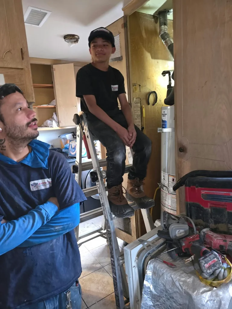 Plumbing technicians working inside a residential property with professional tools.