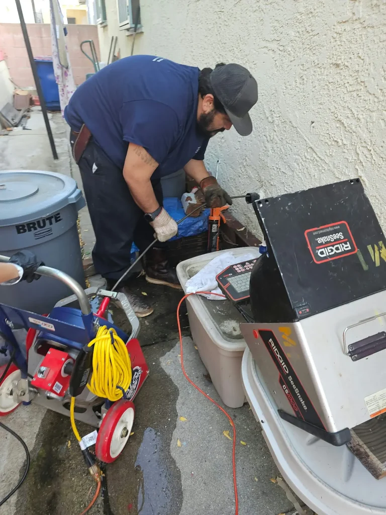 Plumber using professional drain cleaning equipment for pipe service.