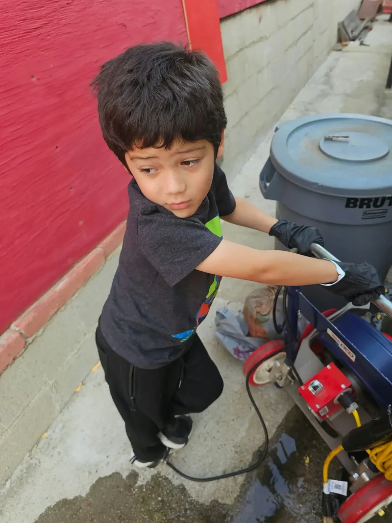 The Kid help out the drain cleaning equipment for pipe service.
